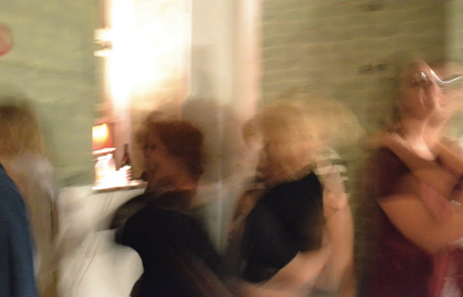 A blurred image shows pairs of people dancing together in lamplit room.