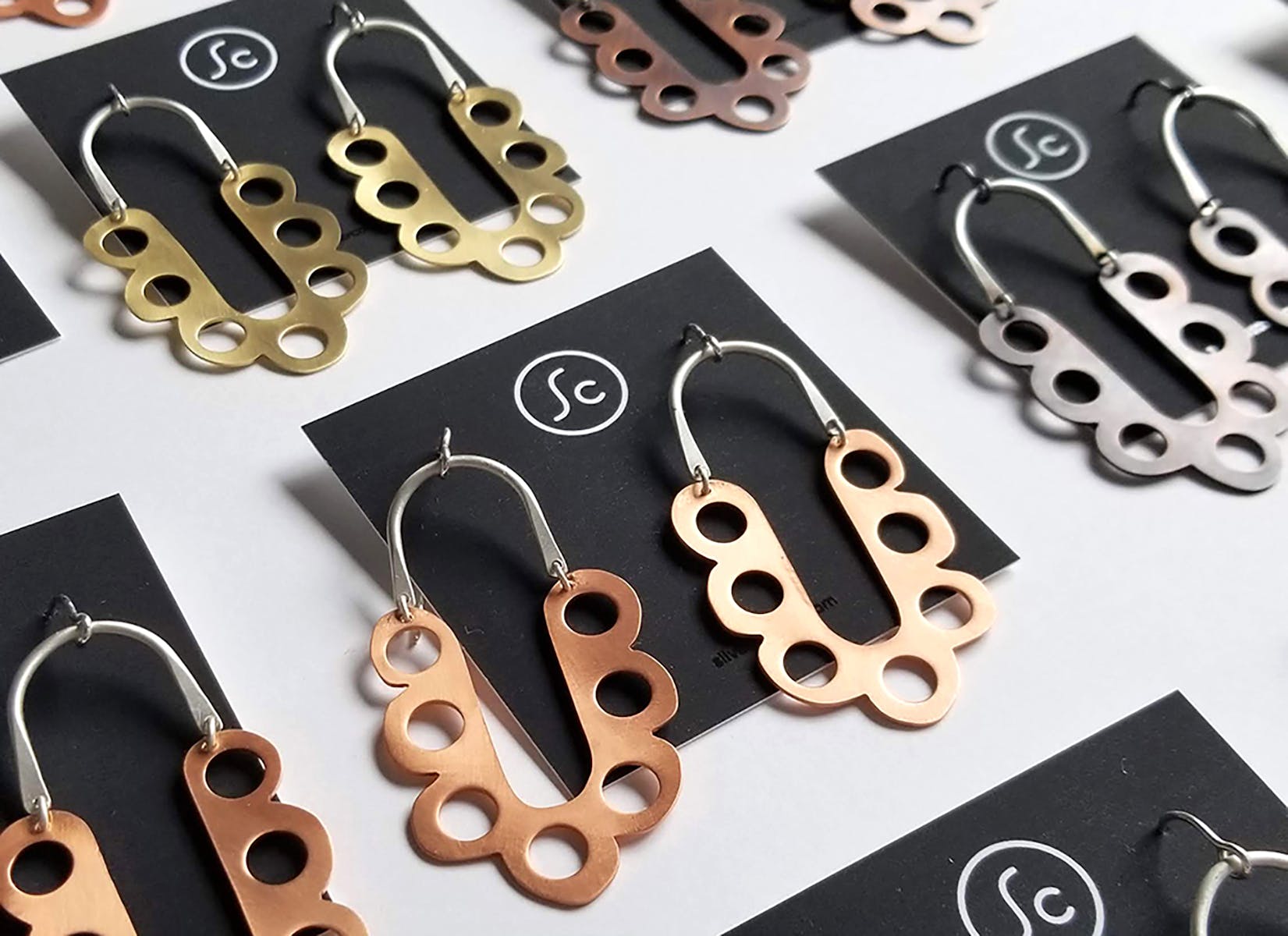 Multiple gold, bronze, and silver earrings featuring geometric patterns