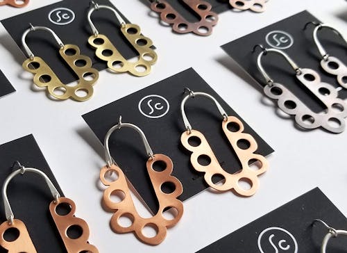 Multiple gold, bronze, and silver earrings featuring geometric patterns