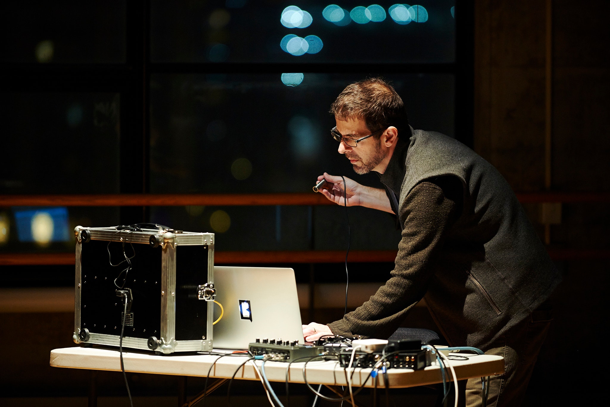 Man standing at laptop with many electric connections.