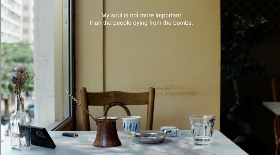 A still-life shot of a chair and tabletop scattered with objects. A caption reads “My soul is not more important than the people dying from the bombs.”