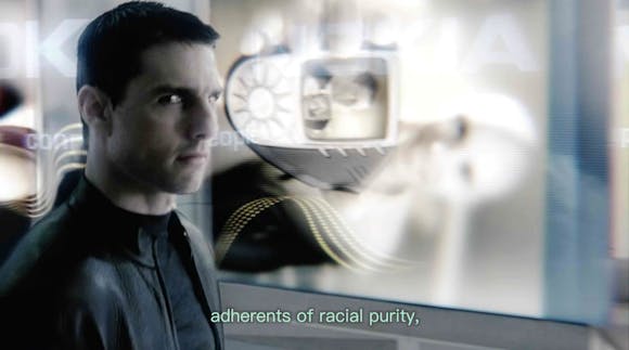 Tom Cruise in front of digital imagery with subtitles “adherents of racial purity,”