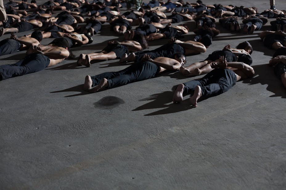 protesters laying on ground with hands behind their backs.