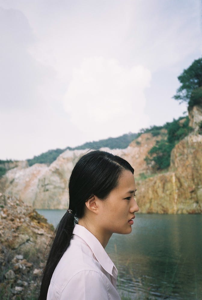 a woman looks out at a river bank.