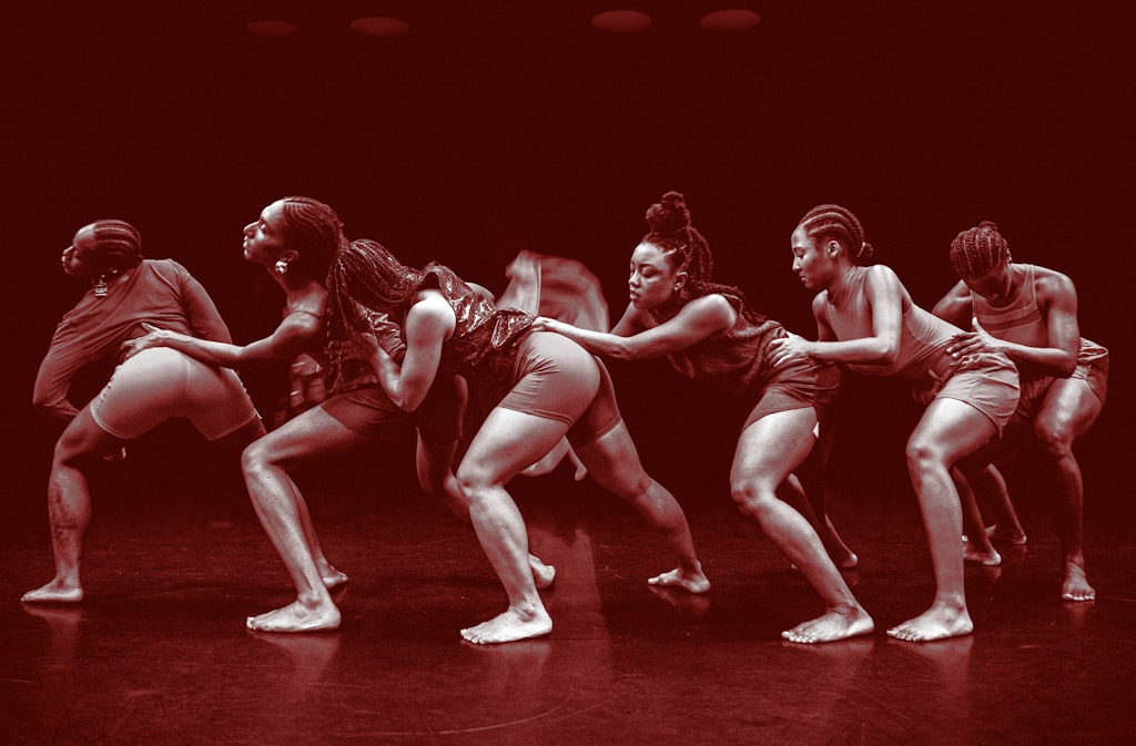 A red tinted image of a line of multiple dancers in profile, crouching in a row with their hands on the waists of those in front of them.
