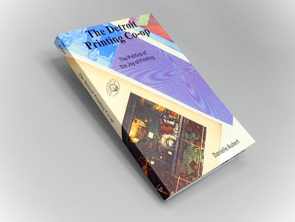 book at an angle on grey background with colorful cover and the title "The Detroit Printing Co-op"