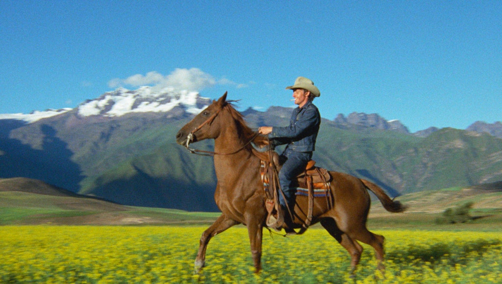 Dennis Hopper riding a horse and smoking a cigarette.