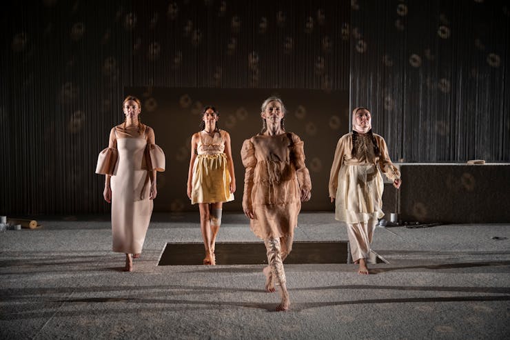 Four dancers walking towards the camera on stage