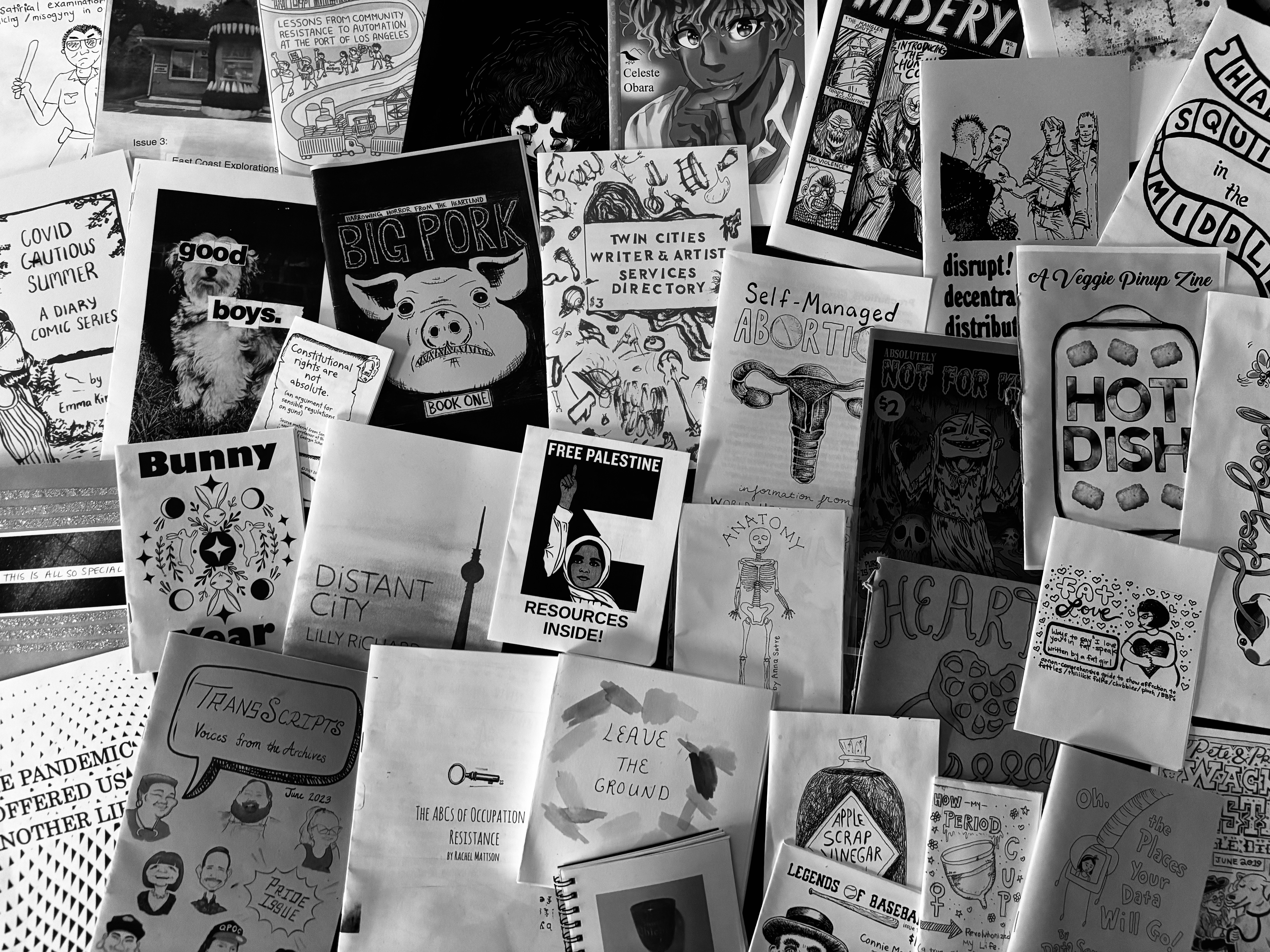 Black and white image of several zines laid out on a table.