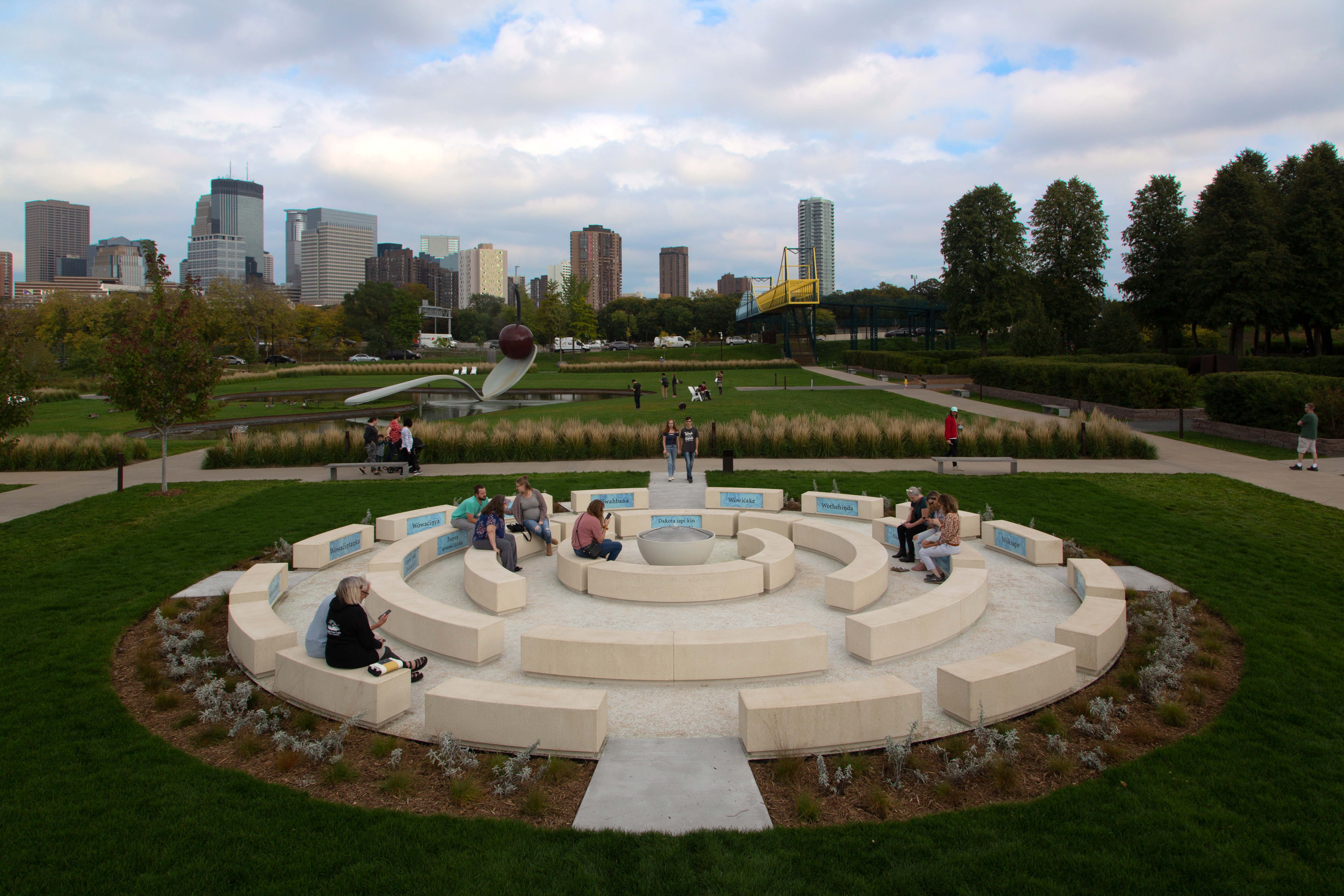 The Walker-commissioned piece, titled Okciyapi (2021), is the first public artwork by a Native artist to be sited in the Garden. Both a gathering place and participatory work, the sculpture is composed of rings of seating elements surrounding a central water feature.