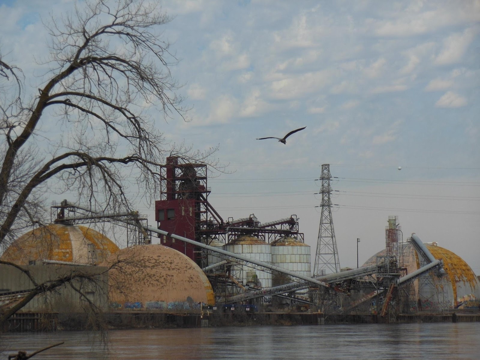 A port with large dome buildings and silos stands on the banks of the Mississippi river.