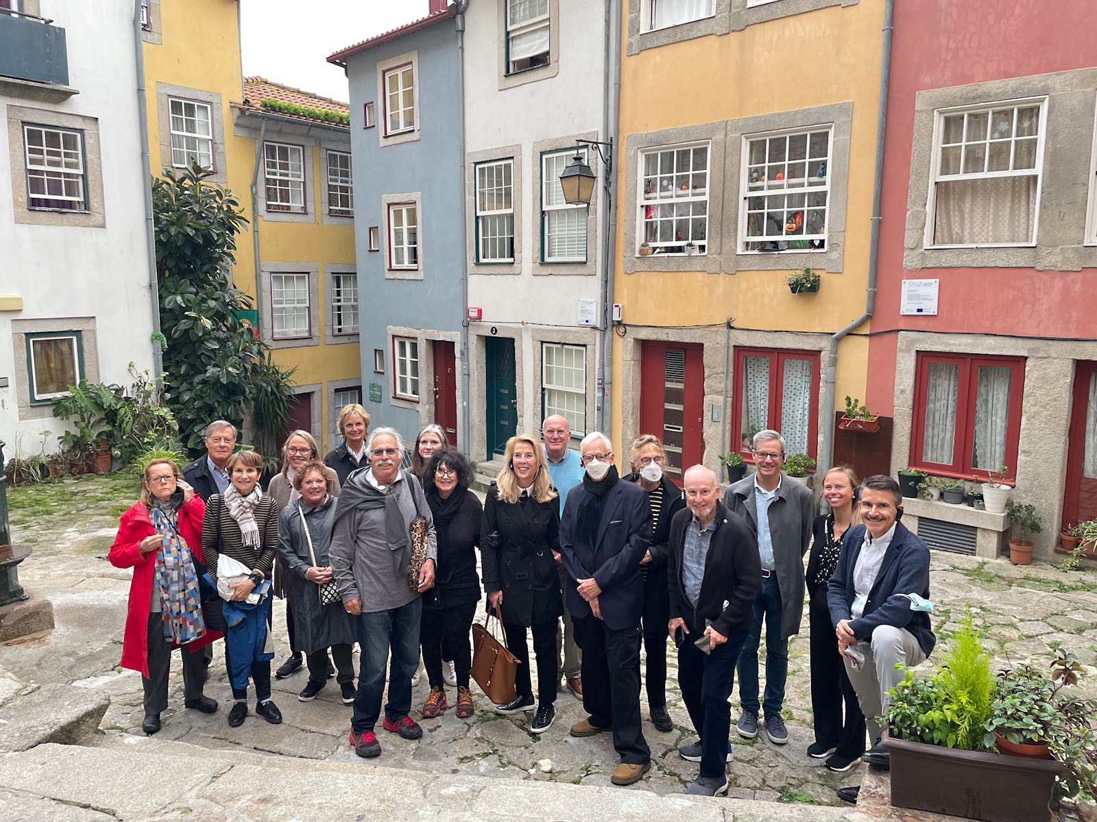 Tour group posing for a photo in front of colorful multi-unit living structure