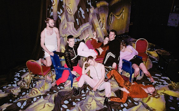 Perfume Genius x Kate Wallich and the YC posing on a multicolored skrim and chairs.