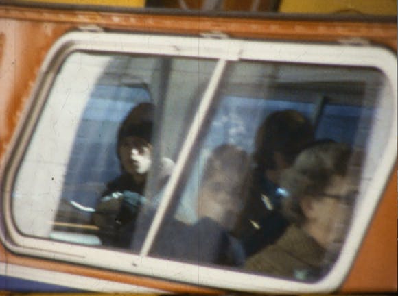 A kid is reflected in the window of a passing vehicle