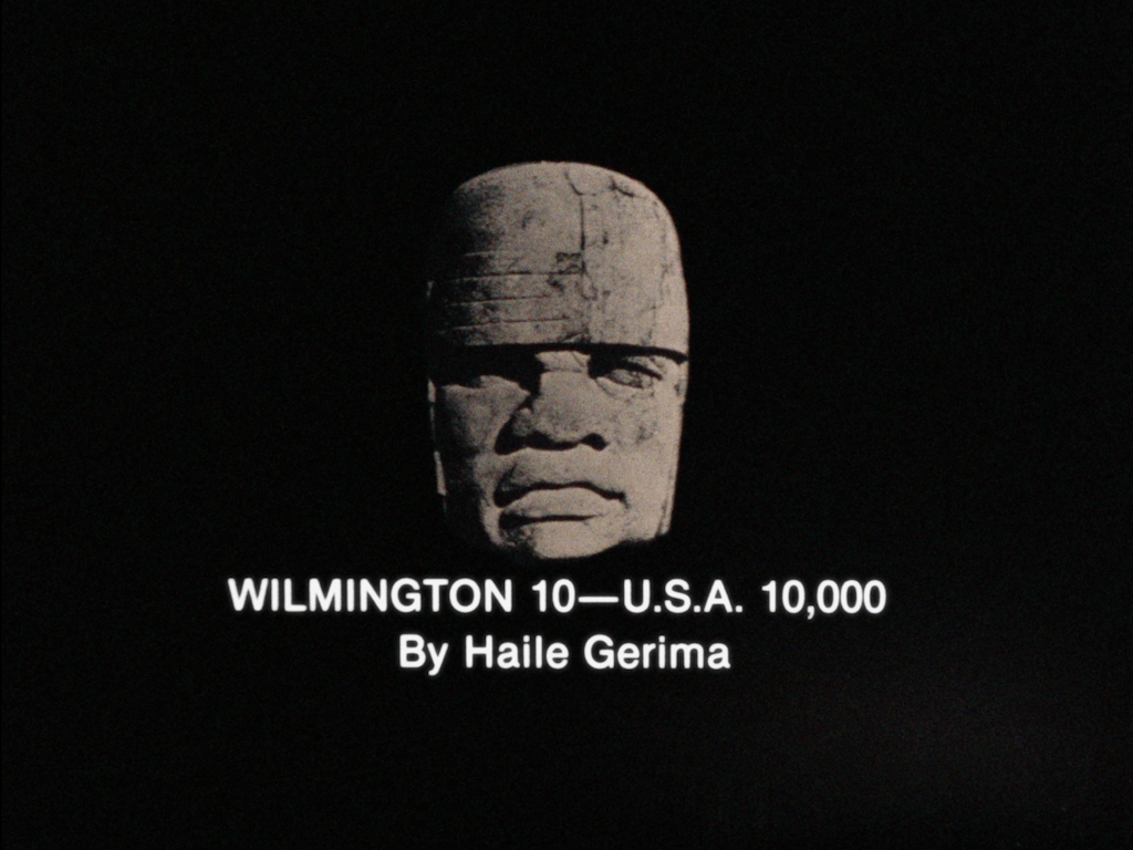 A sculpture of a head sits in black void with the words 