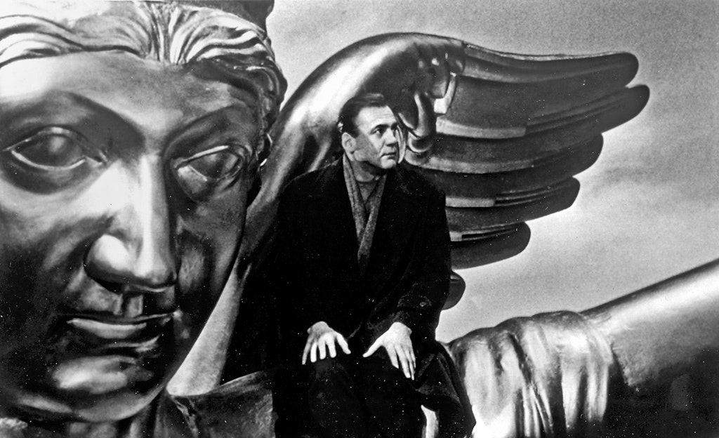 Man sits before wings statue