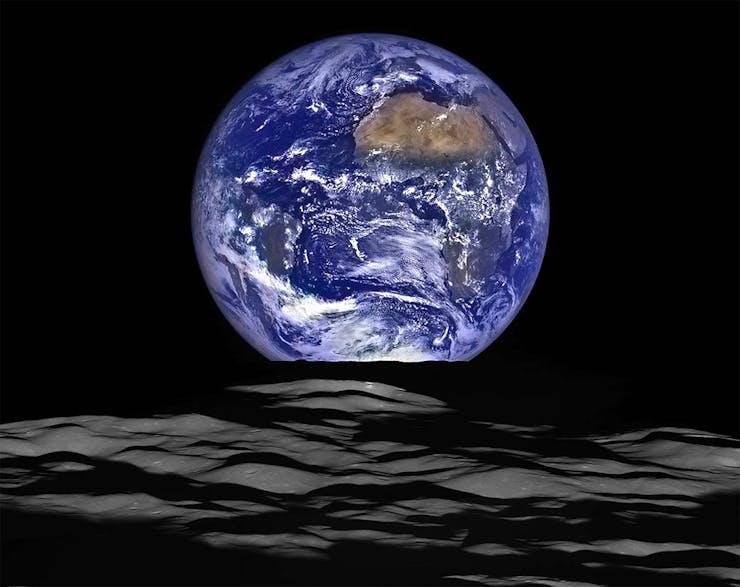 Image of Earth rising from behind the horizon of the moon