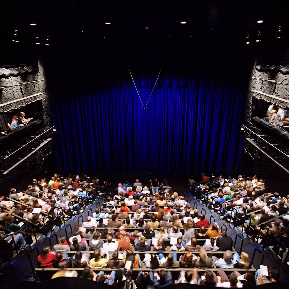 Audience makes their way to seats in a large theater.