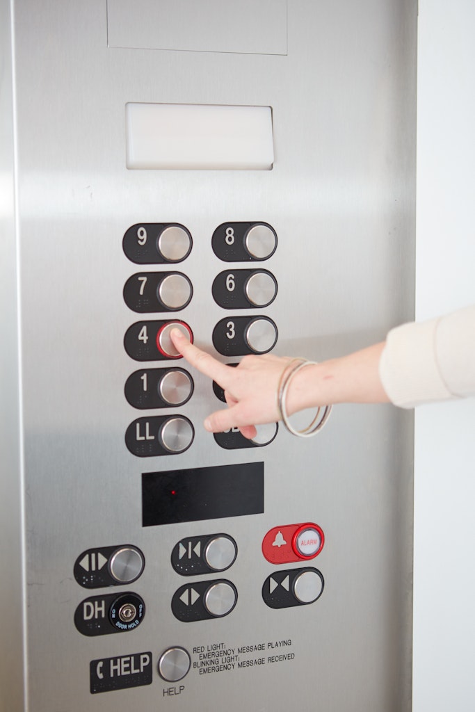 An adult's hand reaches out to select a button marked 