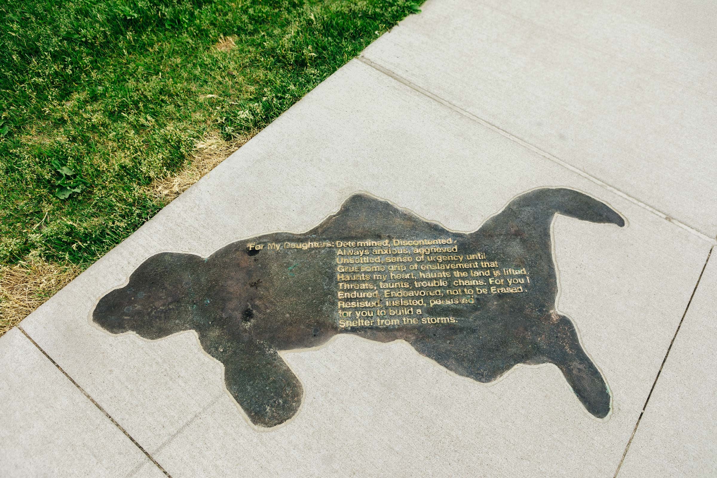 Shadow outline on sidewalk with text of Harriet Robinson Scott poem.