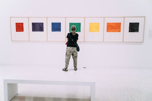 Woman standing in gallery in front of five paintings with colored squares