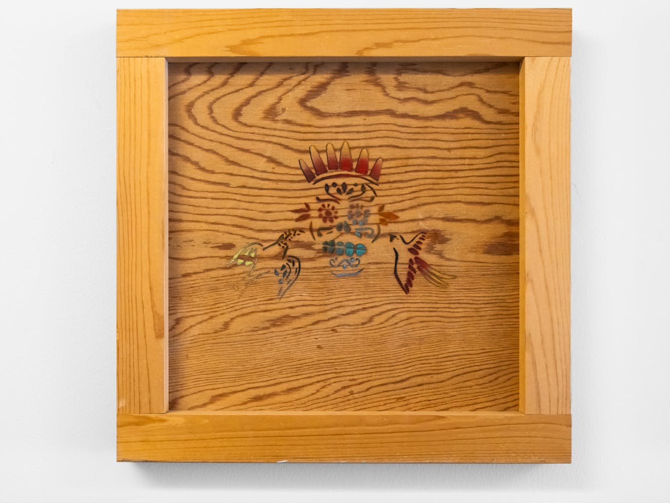 A wood square peice of art with an illustration in the center