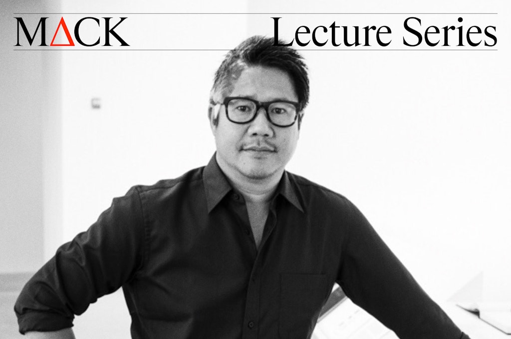 A man in glasses stands with one arm resting on a counter under the text MACK Lecture Series.
