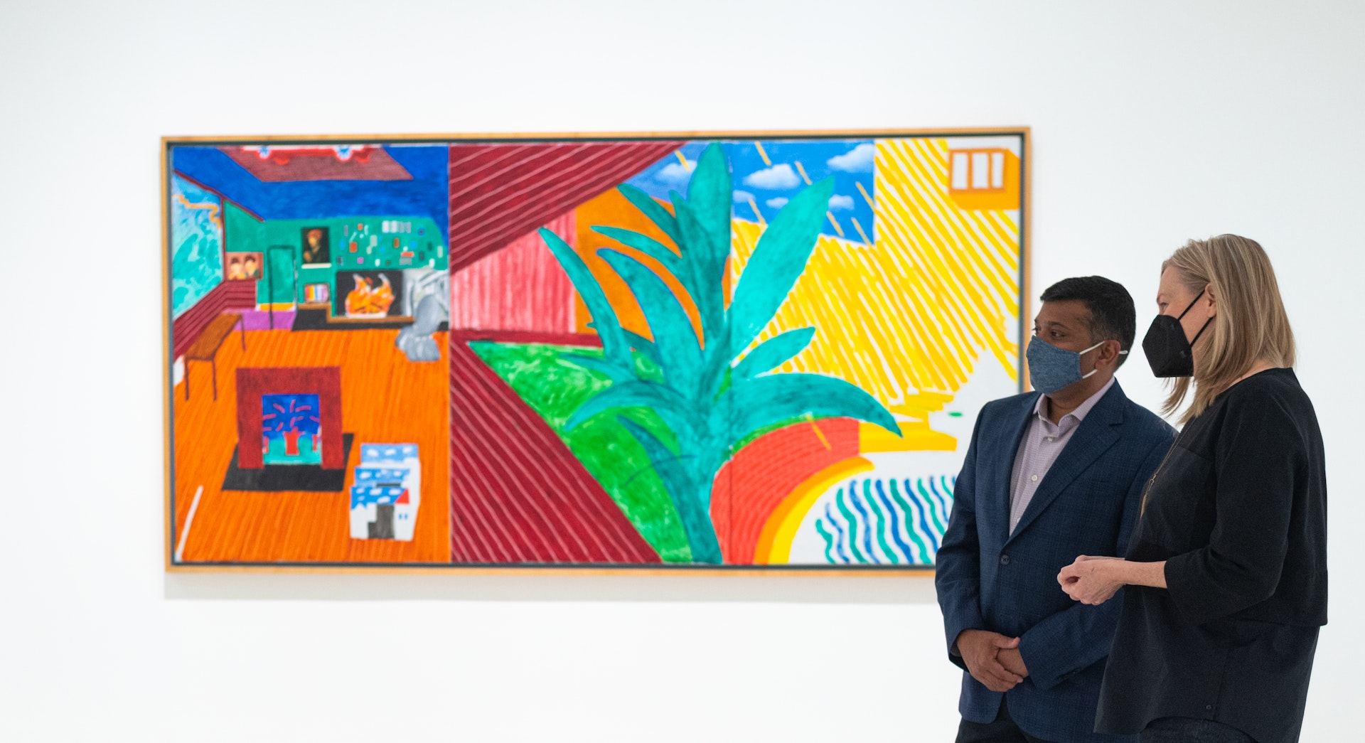 A woman and a man in business attire look at a painting together inside a gallery at the Walker Art Center.