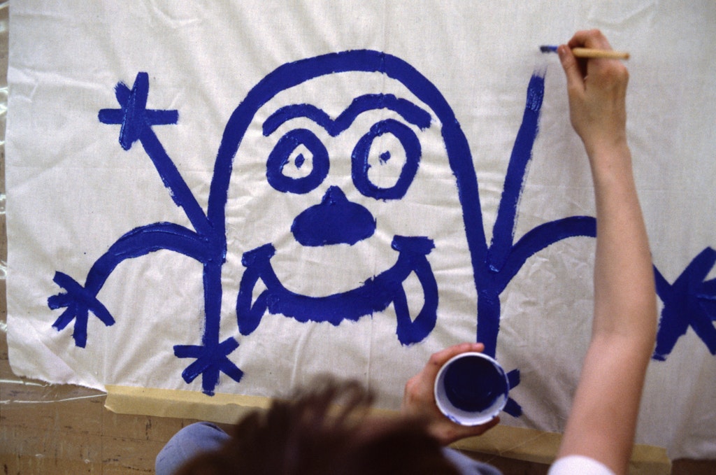 Keith Haring and a child painting a mural on the floor.