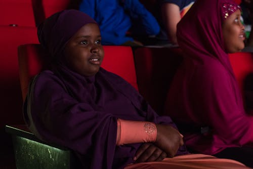 Two children sit in cinema seats watching films