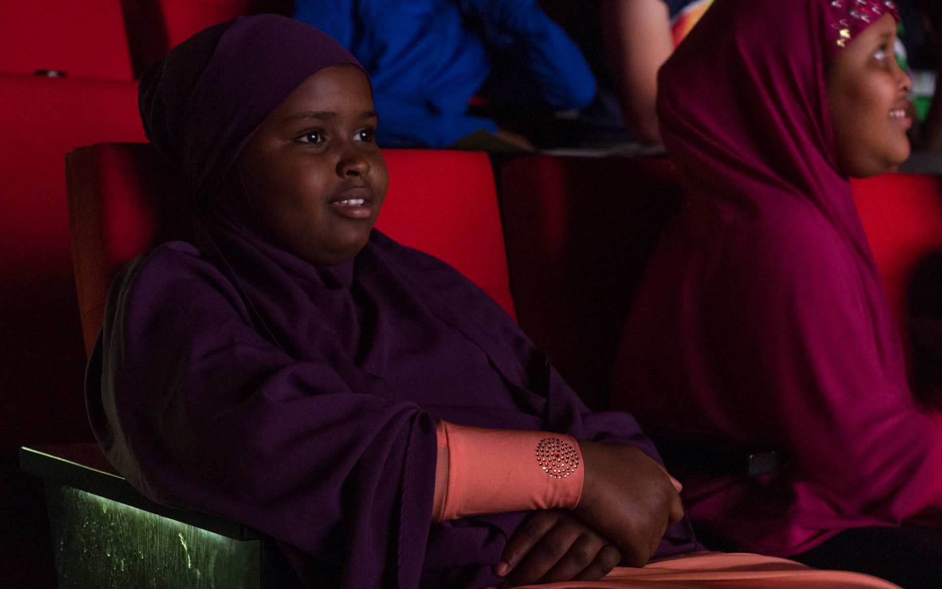 Two children sit in cinema seats watching films