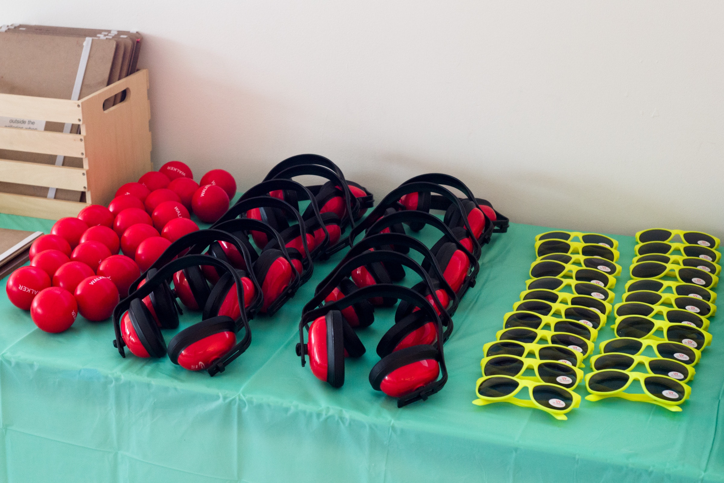 Figet balls, sunglasses, and noise cancelling headphones lie in rows on a table.
