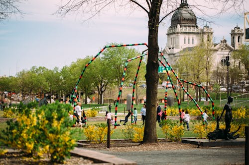 A group of children play in an outdoor sculpture garden with a view of the Minneapolis basilica in the background.