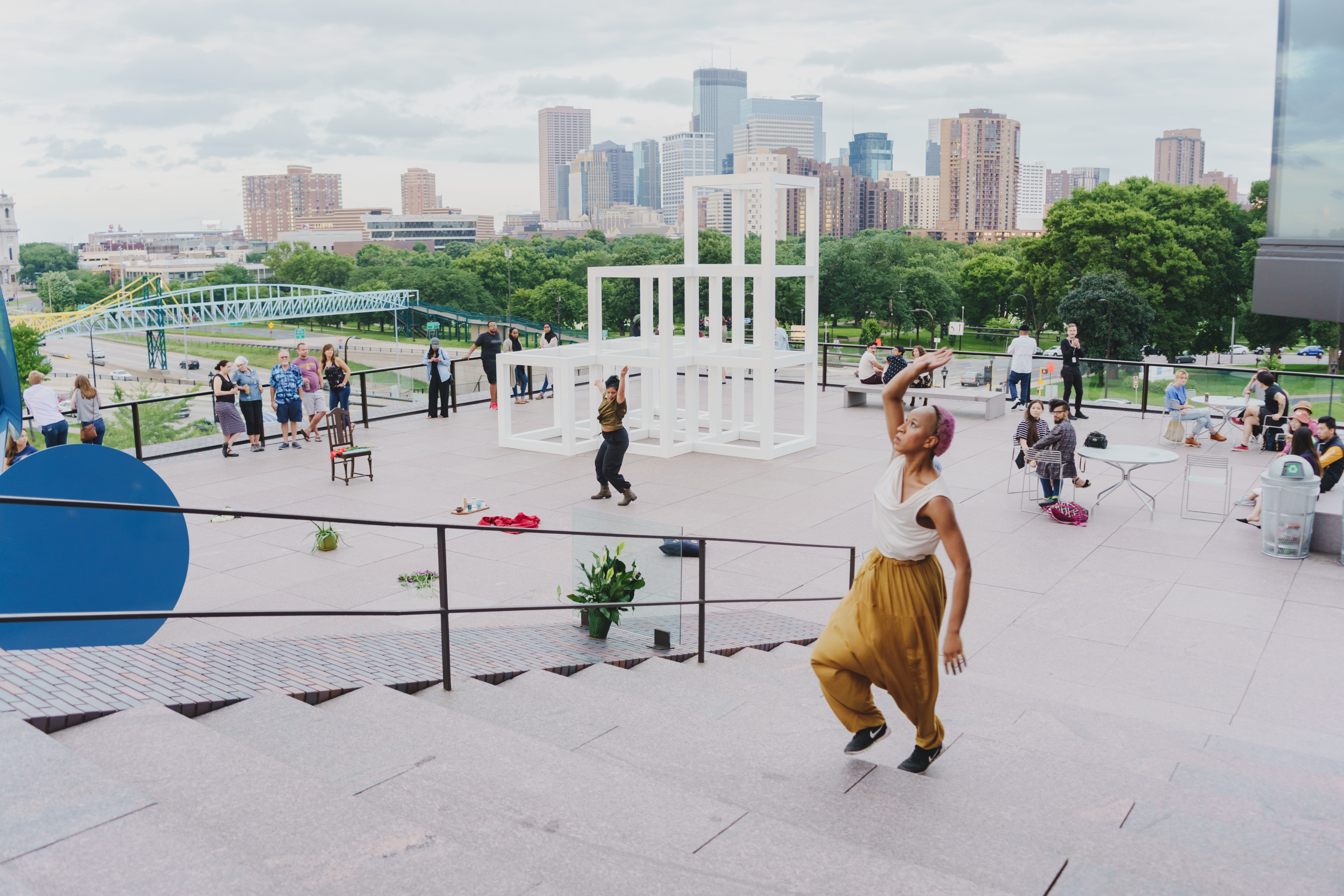 Dancers perform on an outside museum terrace with a view of the Minneapolis city skyline in the background.