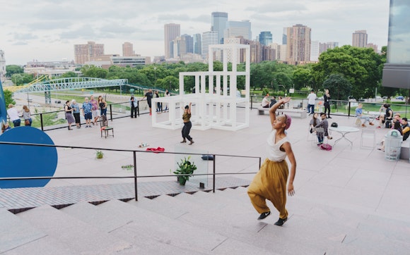 Dancers perform on an outside museum terrace with a view of the Minneapolis city skyline in the background.