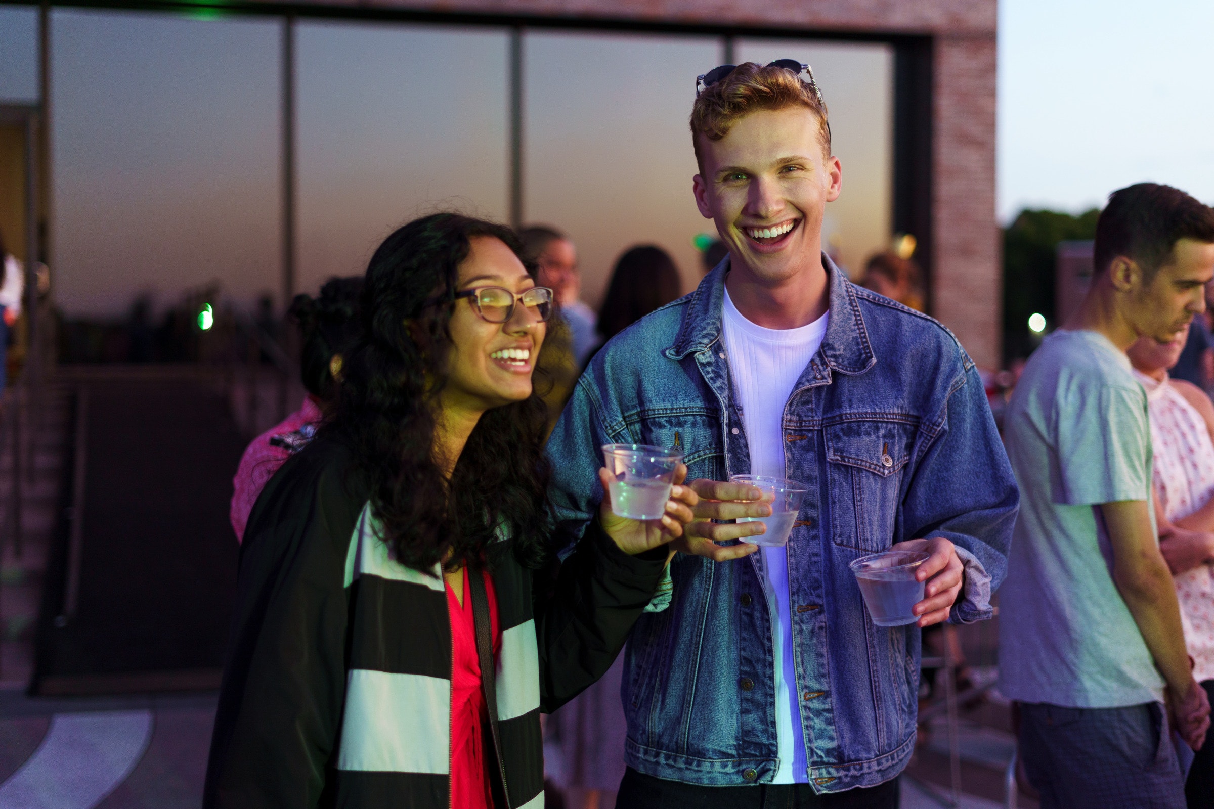 Two people smile and enjoy drinks while they watch the sun set on the Walker’s terraces.
