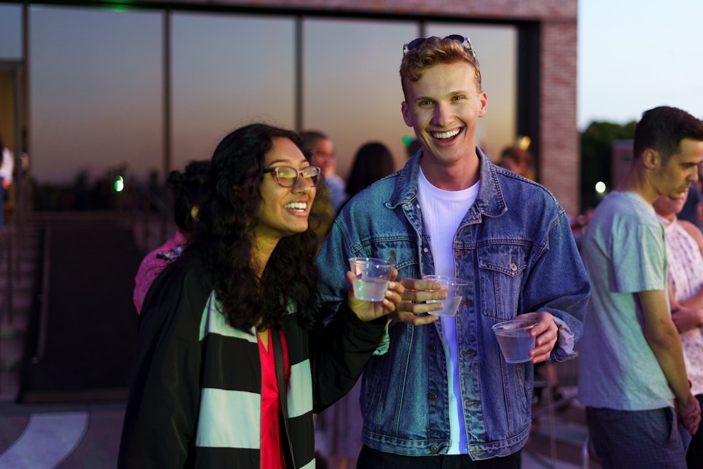 Two people smile and enjoy drinks while they watch the sun set on the Walker’s terraces.