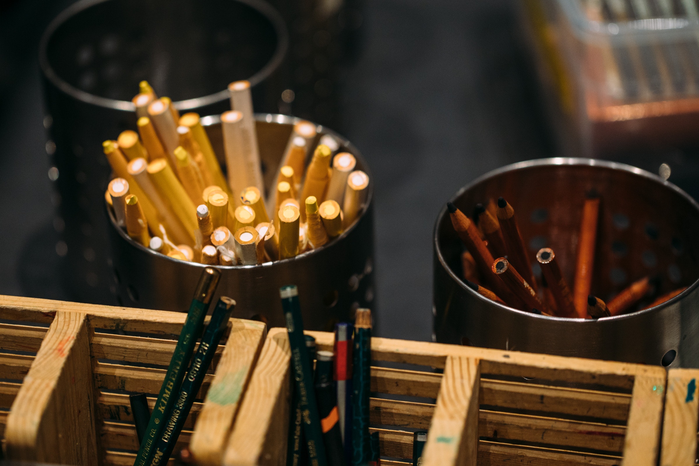 Pencils in metal holders sit on a table.