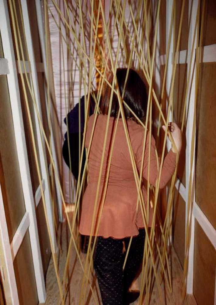 Adults climb through a hallway with frubber tubes streched across the path.