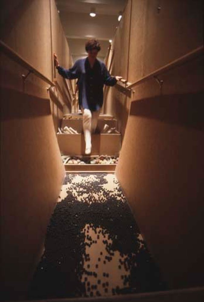 Adults climb through a hallway with floors made of rocks and sand.