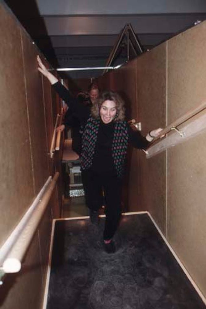 Adults climb through a hallway with floors made of rocks and sand.