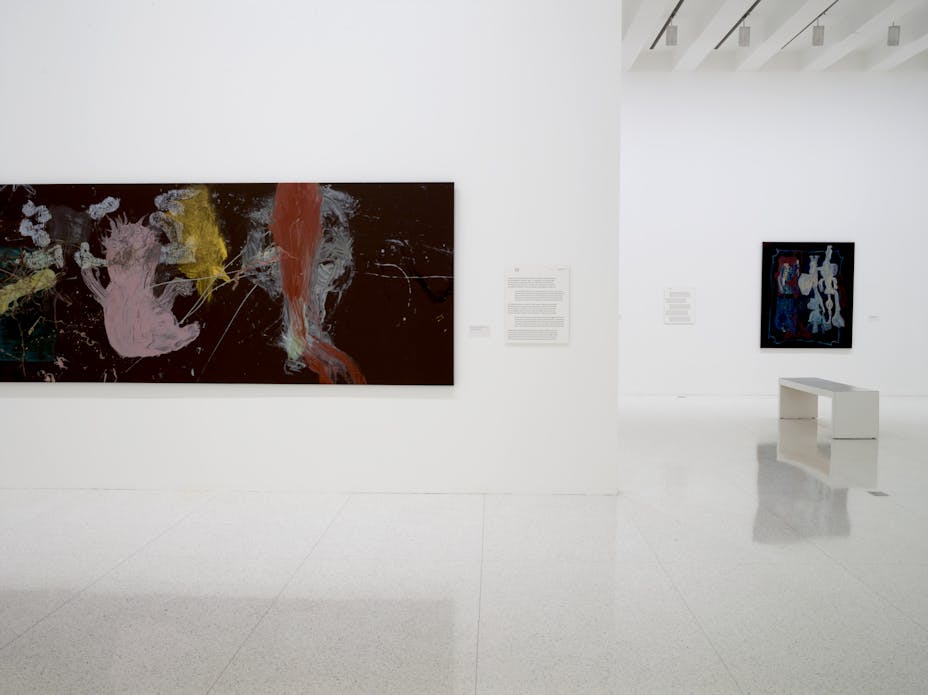 Image of abstract artworks hung on walls in gallery space with white walls.