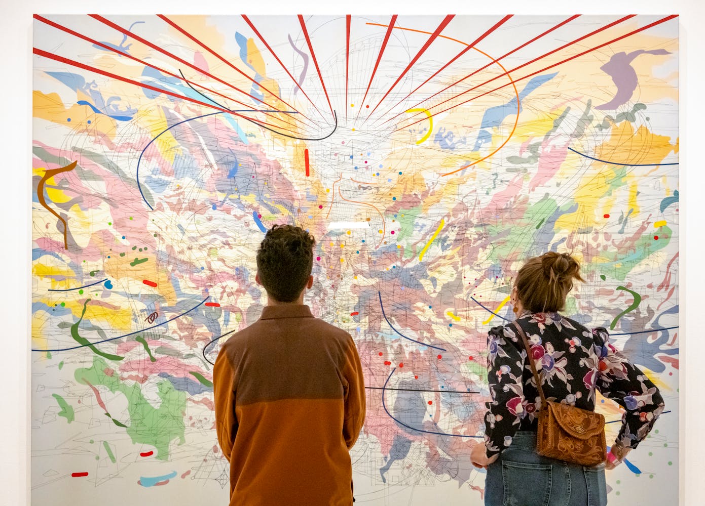 Two people looking at a large, colorful, graphically intricate painting