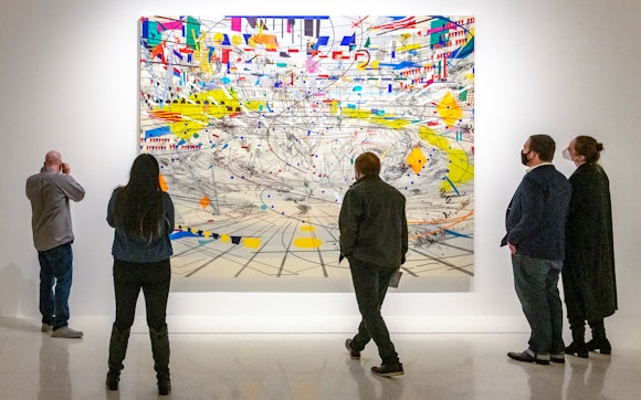 Five people looking at a large, colorful, graphically intricate painting
