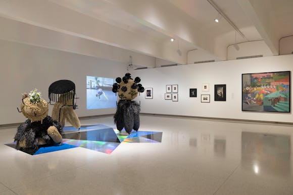 Gallery view with various sculpture objects and projections and paintings