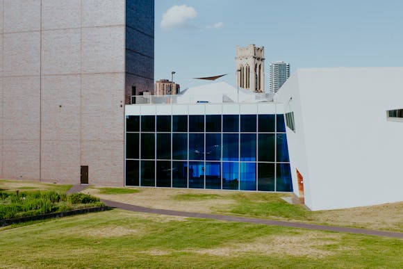 Building with large glass wall covered in blue film, with grass in foreground