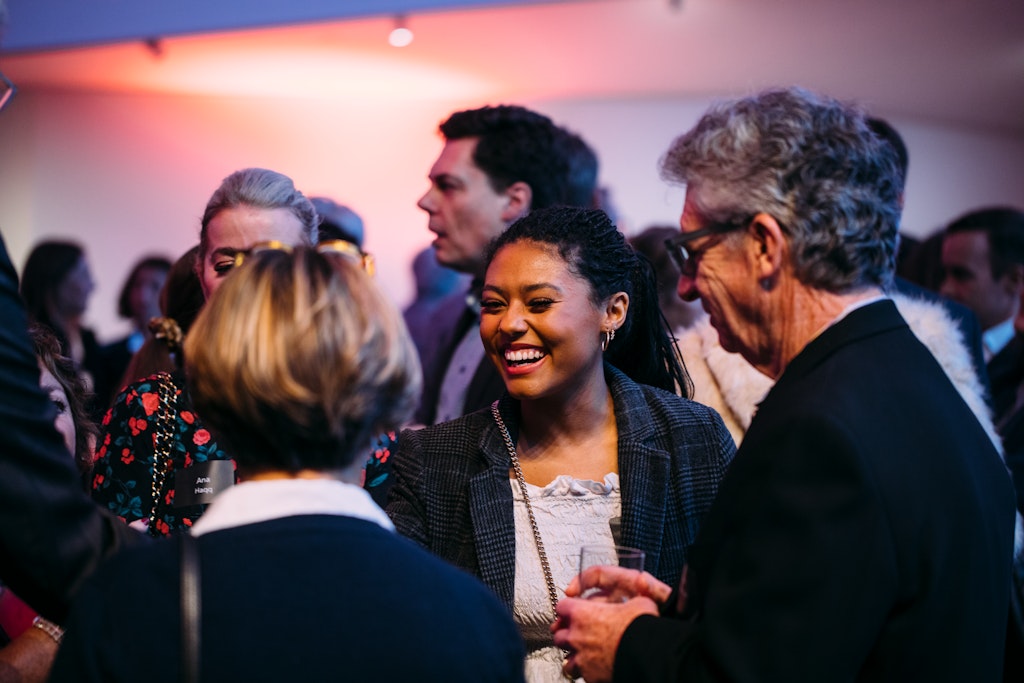A group of people smile as they talk to one another.