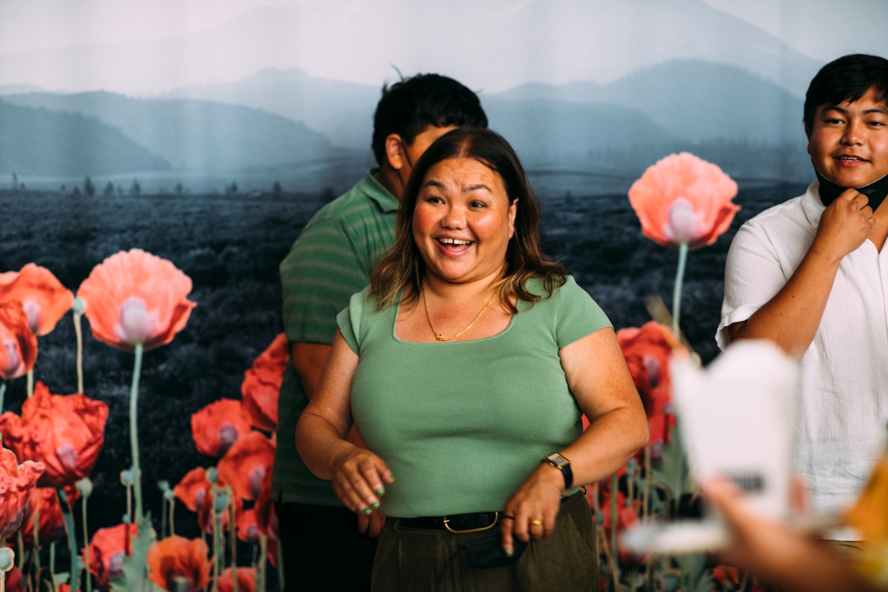A woman stands in from of a mural of flowers and smiles.