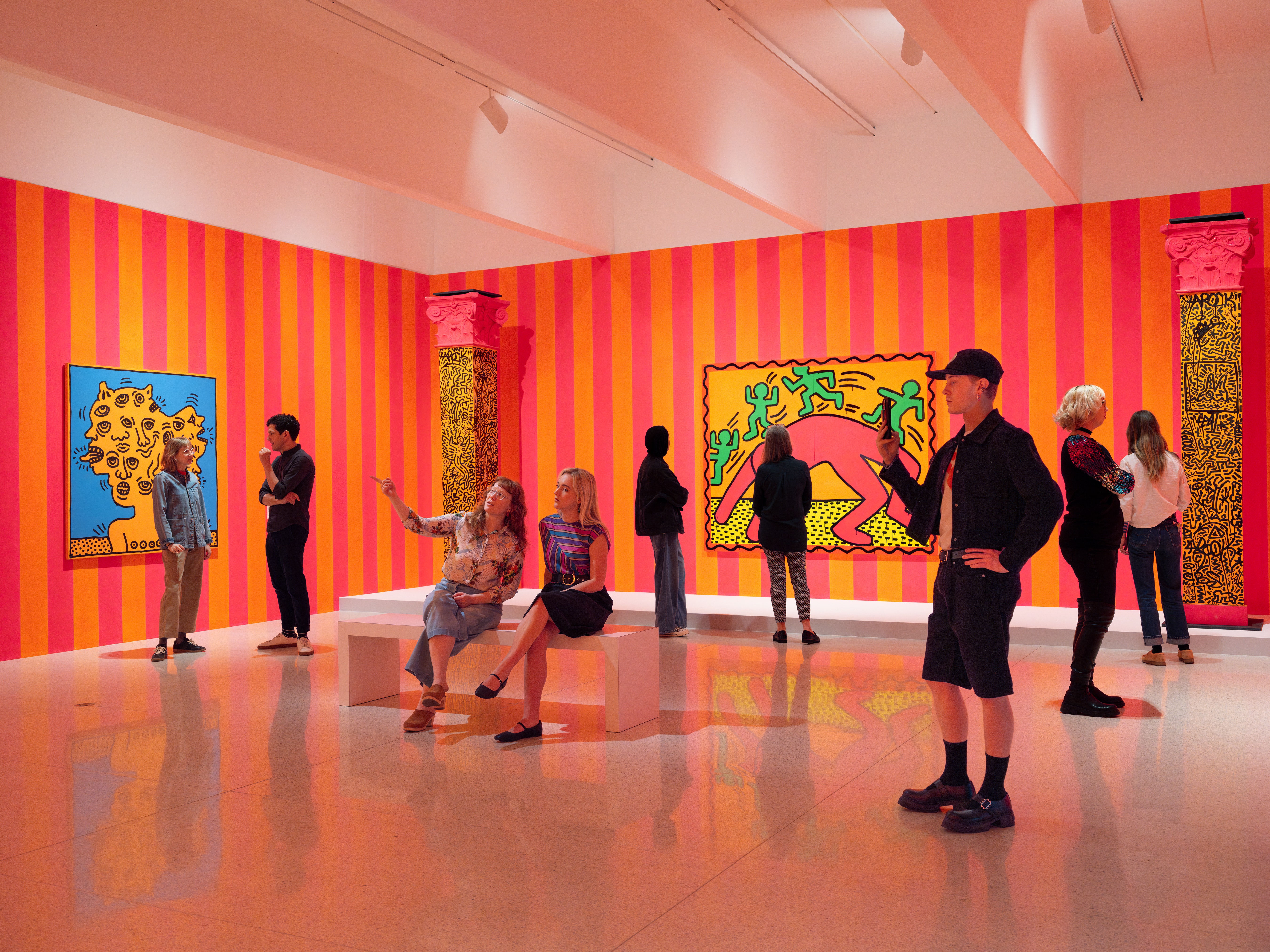 People in a brightly colored gallery looking at art.