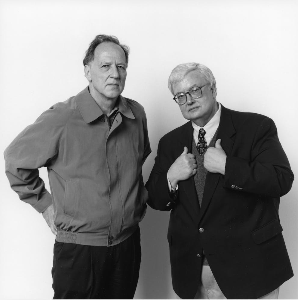 Two men stand next to one another and look int the camera.